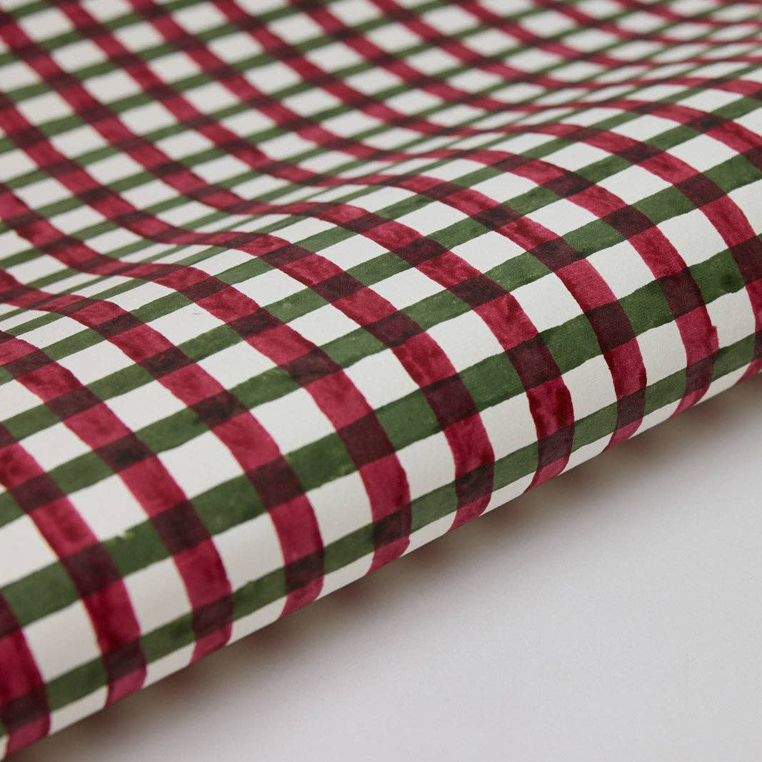 A close-up of a folded fabric with a red, green, and white plaid pattern on a plain white background.