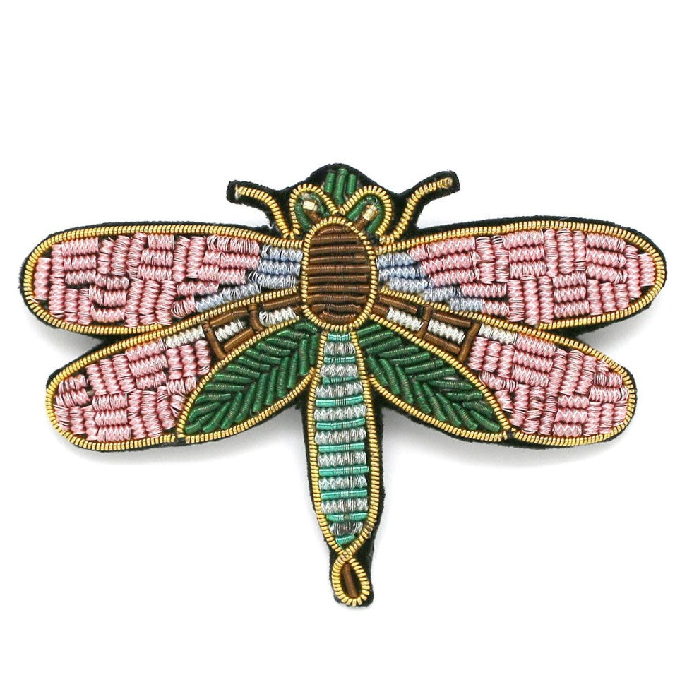 Decorative dragonfly brooch with pink and green patterns on a white background, 