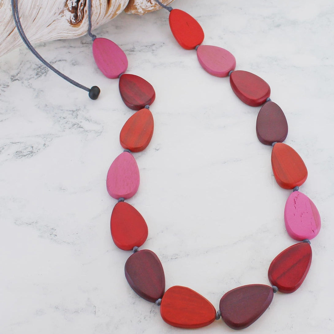 Necklace with pink and red teardrop-shaped beads on a white marble surface.
