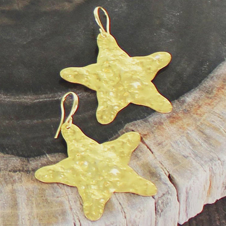 Gold star-shaped earrings on a wooden surface